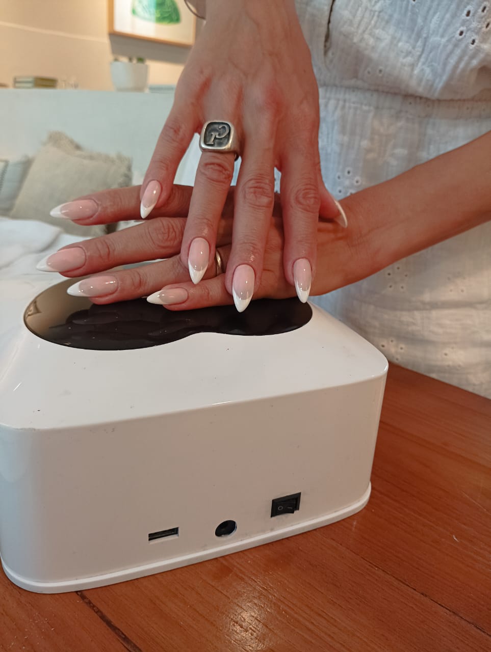 French gel on almond-shaped nails, curing under the lamp